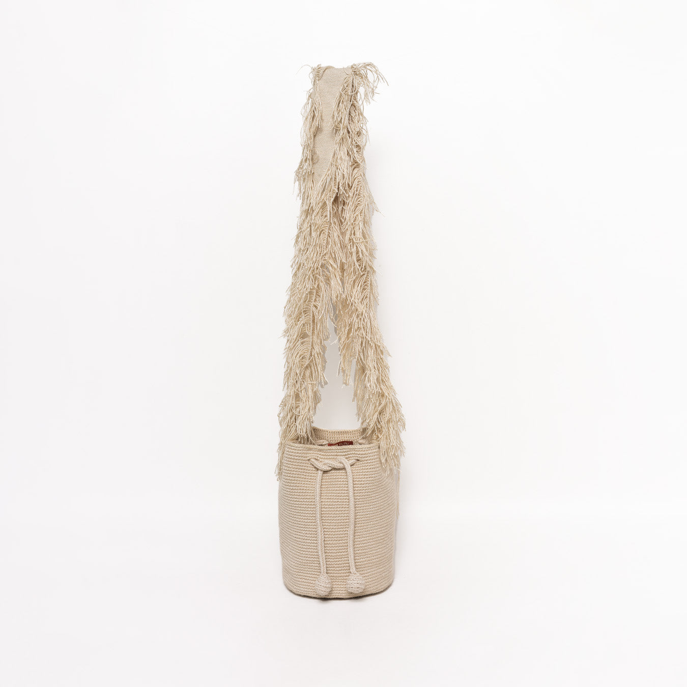 Mochila Flecos, pieza artesanal hecha a mano por artesanas de la comunidad Wayuu en el norte de Colombia. Confeccionada con hilos de algodón y flecos de seda dorada, combina la tradición Wayuu con un diseño vibrante y sofisticado. Su asa larga permite llevarla cruzada, ofreciendo un accesorio único, versátil y lleno de personalidad. Mochila Wayuu, Mochila artesanal, mochila colombiana.