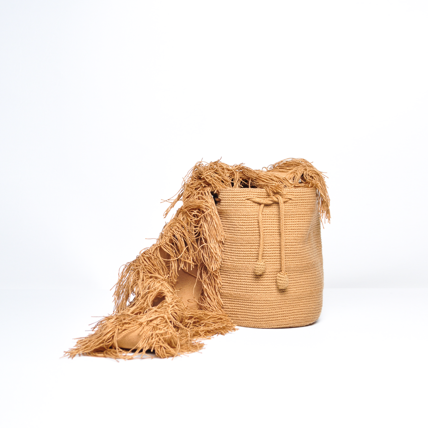 Mochila Flecos, pieza artesanal hecha a mano por artesanas de la comunidad Wayuu en el norte de Colombia. Confeccionada con hilos de algodón y flecos de seda dorada, combina la tradición Wayuu con un diseño vibrante y sofisticado. Su asa larga permite llevarla cruzada, ofreciendo un accesorio único, versátil y lleno de personalidad. Mochila Wayuu, Mochila artesanal, mochila colombiana.