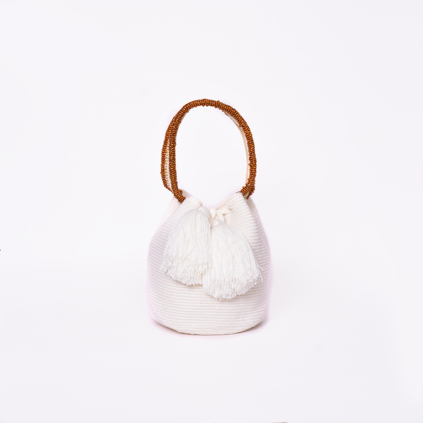 Mochila Suyan artesanal color blanco, tejida a mano por la comunidad Wayuu en el norte de Colombia. Hecha con hilos de algodón y decorada con mostacilla dorada, destaca por su diseño elegante y detalles sofisticados. Mochila de fiesta, mochila wayuu, bolso de fiesta.