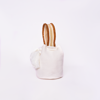Mochila Suyan artesanal color blanco, tejida a mano por la comunidad Wayuu en el norte de Colombia. Hecha con hilos de algodón y decorada con mostacilla dorada, destaca por su diseño elegante y detalles sofisticados. Mochila de fiesta, mochila wayuu, bolso de fiesta.