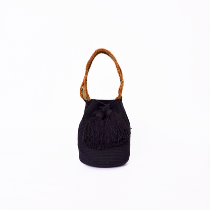 Mochila Suyan artesanal color negro, tejida a mano por la comunidad Wayuu en el norte de Colombia. Hecha con hilos de algodón y decorada con mostacilla dorada, destaca por su diseño elegante y detalles sofisticados. Mochila de fiesta, mochila wayuu, bolso de fiesta.