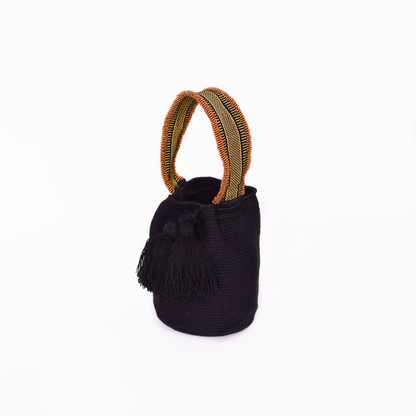 Mochila Suyan artesanal color negro, tejida a mano por la comunidad Wayuu en el norte de Colombia. Hecha con hilos de algodón y decorada con mostacilla dorada, destaca por su diseño elegante y detalles sofisticados. Mochila de fiesta, mochila wayuu, bolso de fiesta.