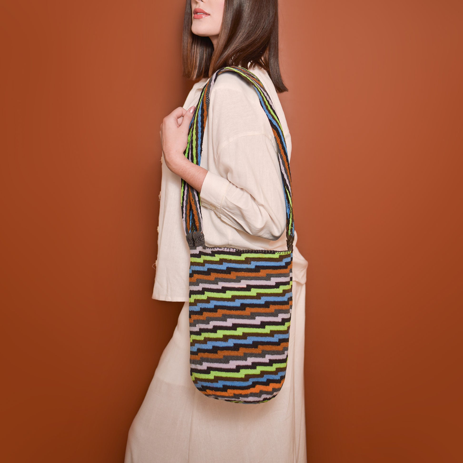 Mochila Poporo, bolso artesanal colombiano tejido a mano por artesanas Arhuacas de la Sierra Nevada. Elaborada con lana de oveja e hilos de algodón teñidos con tintes naturales. Incluye gasa de largo especial y diseño funcional que respeta la tradición Arhuaca. Pieza única que representa el conocimiento ancestral y la conexión con la naturaleza.