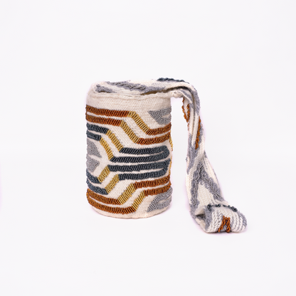 Mochila Paz, bolso artesanal recamado y hecho a mano con lana por artesanas de la comunidad Kankuama en la Sierra Nevada de Colombia. Su diseño exclusivo, adornado con mostacillas y gasa larga, refleja la identidad cultural y el arte de esta comunidad indígena. Cada pieza es única, fusionando tradición y elegancia en un accesorio versátil y auténtico.