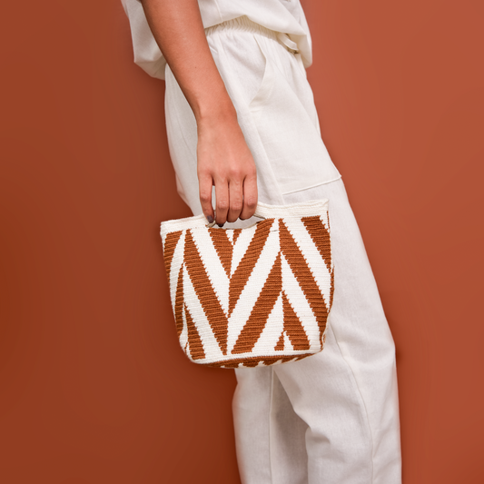 Sobre Lola Wayuu, bolso artesanal hecho a mano por talentosas artesanas de la comunidad Wayuu en el norte de Colombia. Este accesorio único fusiona la tradición y la modernidad con sus patrones geométricos y textura de alta calidad. Tejido a mano con hilos de algodón, es un bolso versátil y elegante, perfecto para llevar lo esencial con estilo.