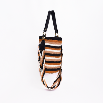Mochila Ruth, pieza artesanal hecha a mano por artesanas de la comunidad Kankuama en la Sierra Nevada de Colombia. Su diseño innovador combina tradición y modernidad, con doble asa: una tejida a mano y extraíble mediante ganchos, y otra en cuero para un toque sofisticado. Esta mochila refleja la identidad cultural y habilidad excepcional de las artesanas Kankuamas.
