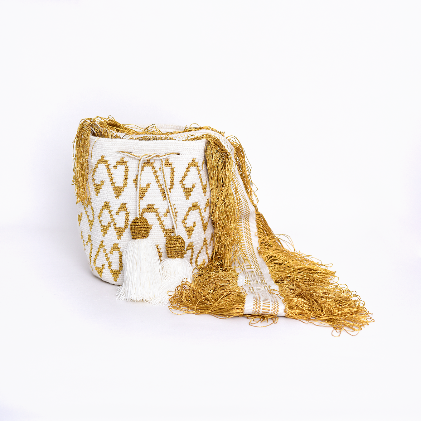 Mochila Fefi, mini mochila artesanal hecha a mano por artesanas de la comunidad Wayuu en el norte de Colombia. Confeccionada con hilos de algodón y flecos de seda dorada, fusiona la tradición del tejido Wayuu con un diseño sofisticado. Su asa larga permite llevarla cruzada, ofreciendo un accesorio versátil, único y funcional.