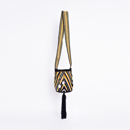 Mochila Nadina, bolso artesanal colombiano tejido a mano por artesanas Wayuu con hilos de algodón. Incluye asa larga, gasa ajustable, detalles únicos y bailarina colgante. Pieza única que combina tradición, cultura y estilo."