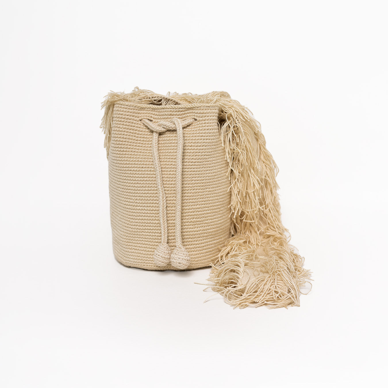 Mochila Flecos, pieza artesanal hecha a mano por artesanas de la comunidad Wayuu en el norte de Colombia. Confeccionada con hilos de algodón y flecos de seda dorada, combina la tradición Wayuu con un diseño vibrante y sofisticado. Su asa larga permite llevarla cruzada, ofreciendo un accesorio único, versátil y lleno de personalidad. Mochila Wayuu, Mochila artesanal, mochila colombiana.