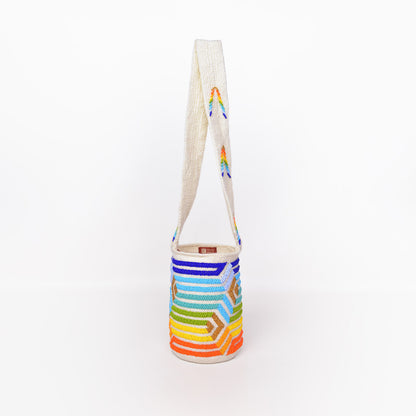 Mochila Paz, bolso artesanal recamado y hecho a mano con lana por artesanas de la comunidad Kankuama en la Sierra Nevada de Colombia. Su diseño exclusivo, adornado con mostacillas y gasa larga, refleja la identidad cultural y el arte de esta comunidad indígena. Cada pieza es única, fusionando tradición y elegancia en un accesorio versátil y auténtico.