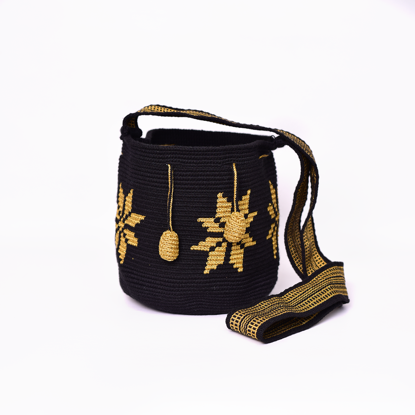 Mochila Marlen, mochila artesanal hecha a mano por artesanas de la comunidad Wayuu en el norte de Colombia. Tejida con hilos de algodón y seda dorada. Su diseño de flores tejidas aporta elegancia atemporal, mientras que su gasa larga y cordón ajustable. Mochila wayuu, mochila colombiana, bolso colombiano, bolso artesanal, mochila artesanal.