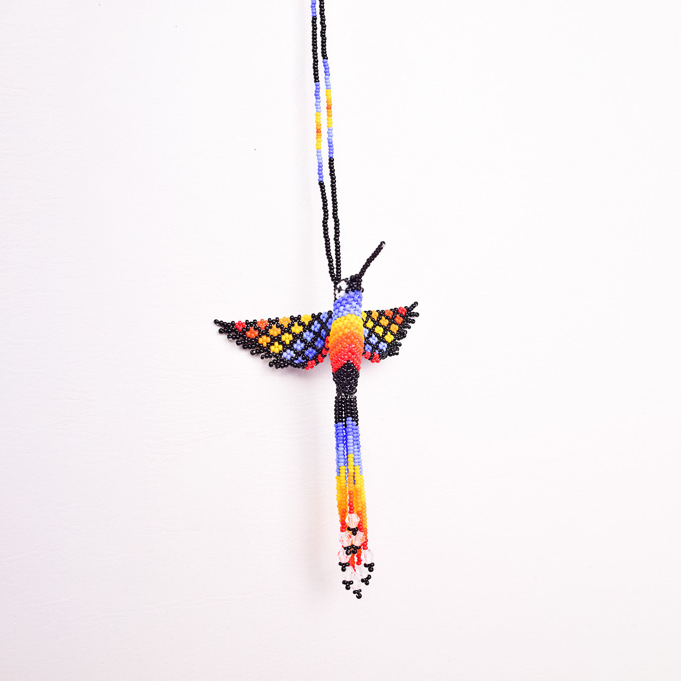 Collar Colibrí artesanal, tejido a mano con mostacillas por la comunidad Emberá en Colombia. Diseño colorido inspirado en el colibrí, símbolo de alegría y libertad.