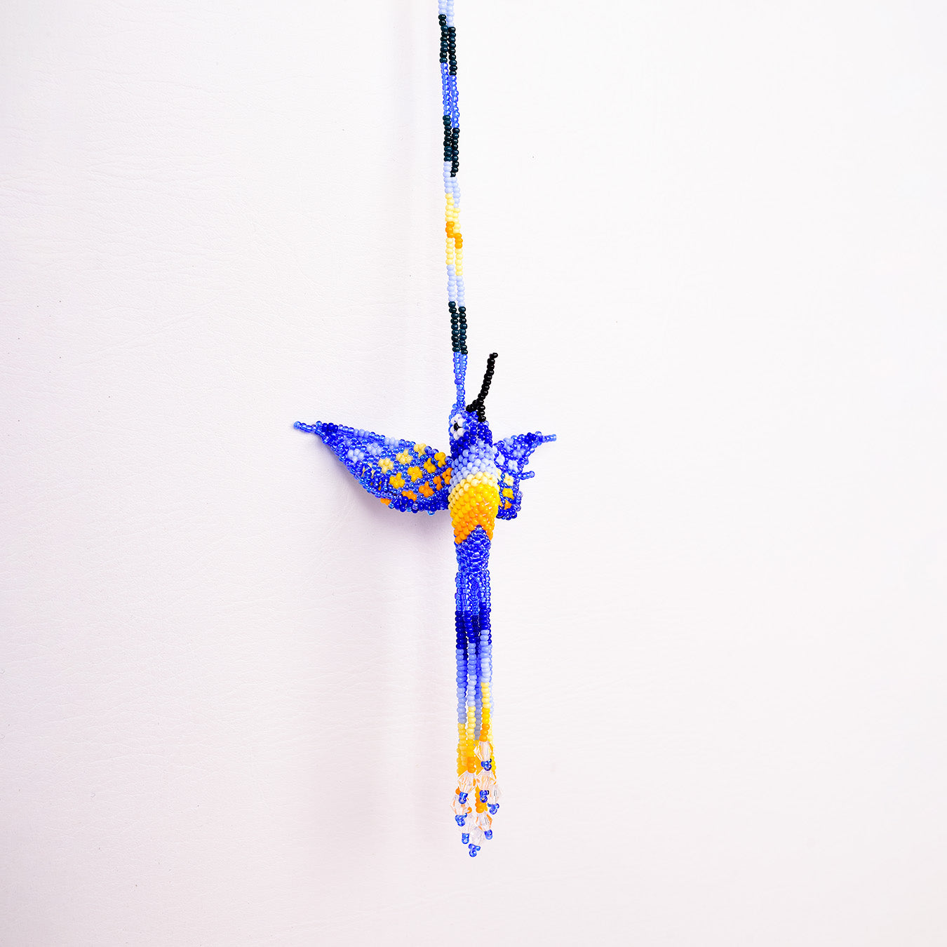 Collar Colibrí artesanal, tejido a mano con mostacillas por la comunidad Emberá en Colombia. Diseño colorido inspirado en el colibrí, símbolo de alegría y libertad.