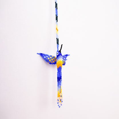 Collar Colibrí artesanal, tejido a mano con mostacillas por la comunidad Emberá en Colombia. Diseño colorido inspirado en el colibrí, símbolo de alegría y libertad.