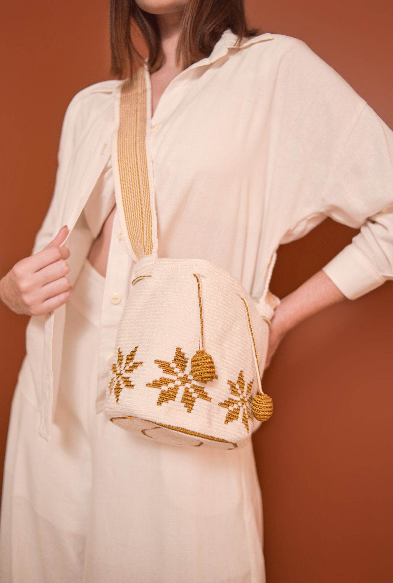 Mochila Marlen, mochila artesanal hecha a mano por artesanas de la comunidad Wayuu en el norte de Colombia. Tejida con hilos de algodón y seda dorada. Su diseño de flores tejidas aporta elegancia atemporal, gasa larga y cordón ajustable. Mochila wayuu, mochila colombiana, bolso colombiano, bolso artesanal, mochila artesanal, color blanco.