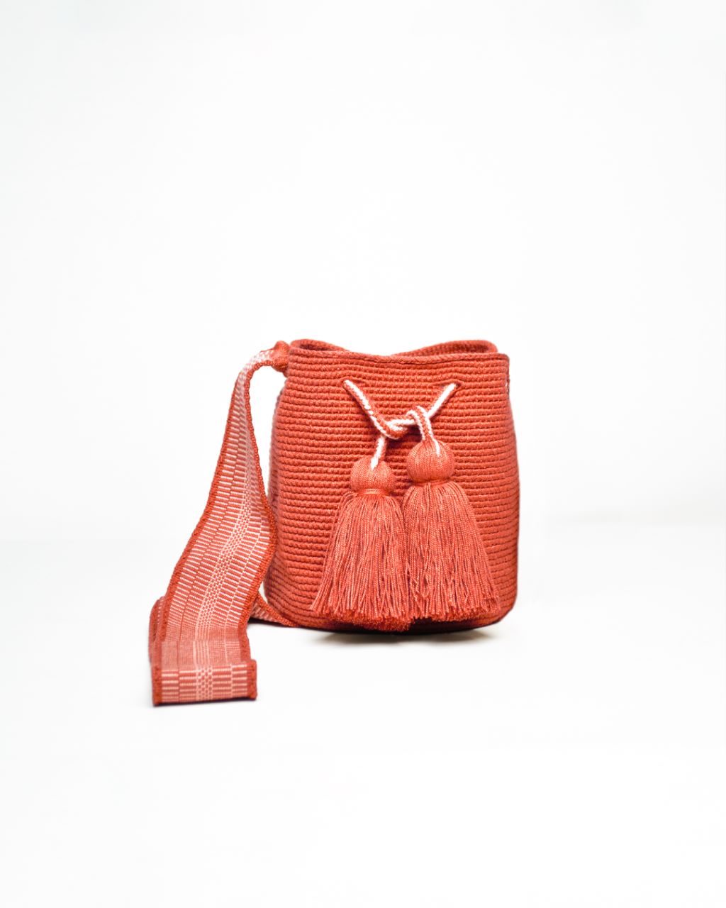 Mochila Amaranta Wayuu, elaborada a mano por artesanas de la comunidad Wayuu en el norte de La Guajira, Colombia. Esta mochila única destaca por su diseño auténtico y práctico, tejida 100% a mano con dedicación. Cuenta con un asa larga para llevarla cómodamente al hombro o cruzada, y dos bailarinas ajustables que no solo aportan un toque decorativo, sino que también garantizan un cierre seguro para proteger tus pertenencias. Color naranja.