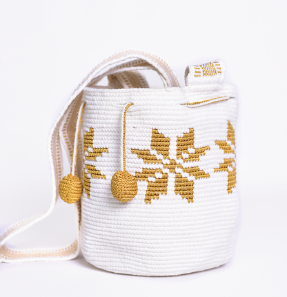 Mochila Marlen, mochila artesanal hecha a mano por artesanas de la comunidad Wayuu en el norte de Colombia. Tejida con hilos de algodón y seda dorada. Su diseño de flores tejidas aporta elegancia atemporal, mientras que su gasa larga y cordón ajustable. Mochila wayuu, mochila colombiana, bolso colombiano, bolso artesanal, mochila artesanal.