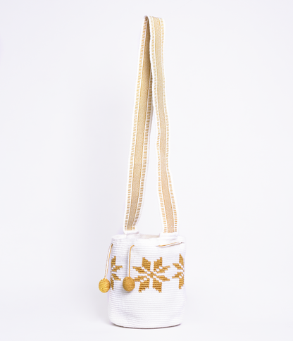Mochila Marlen, mochila artesanal hecha a mano por artesanas de la comunidad Wayuu en el norte de Colombia. Tejida con hilos de algodón y seda dorada. Su diseño de flores tejidas aporta elegancia atemporal, mientras que su gasa larga y cordón ajustable. Mochila wayuu, mochila colombiana, bolso colombiano, bolso artesanal, mochila artesanal, color blanco.