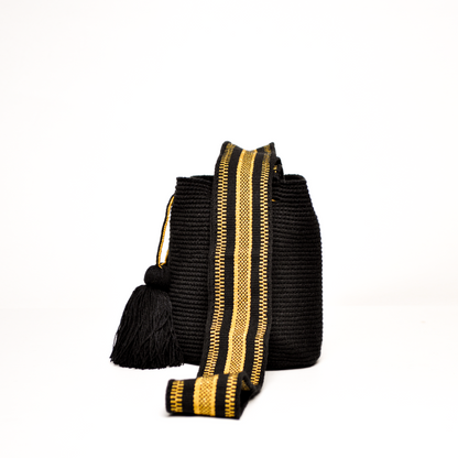 Mochila Sami, mini mochila Wayuu hecha a mano por artesanas de la comunidad Wayuu en La Guajira, Colombia. Tejida con hilos brillantes, su diseño delicado y sofisticado se complementa con una asa larga que aporta un toque elegante y versátil. 